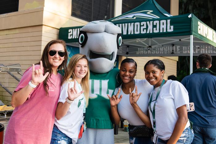 Four students posing with the mascot, Dunkin. 